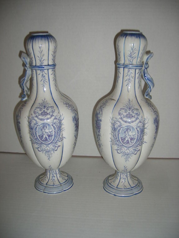 Pair of porcelian vases with painted floral decoration and putti in medallions.<br />
Blue on white.<br />
14