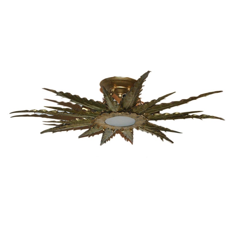 Large sunburst gilt metal light fixture with frosted glass inset.

Measurements:
diameter: 27″
drop: 5″

