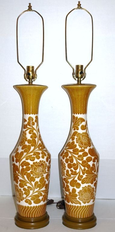 A pair of French, 1940s glazed porcelain table lamps with stylized floral and foliage decoration, Wooden bases. 
Measures: 25.5