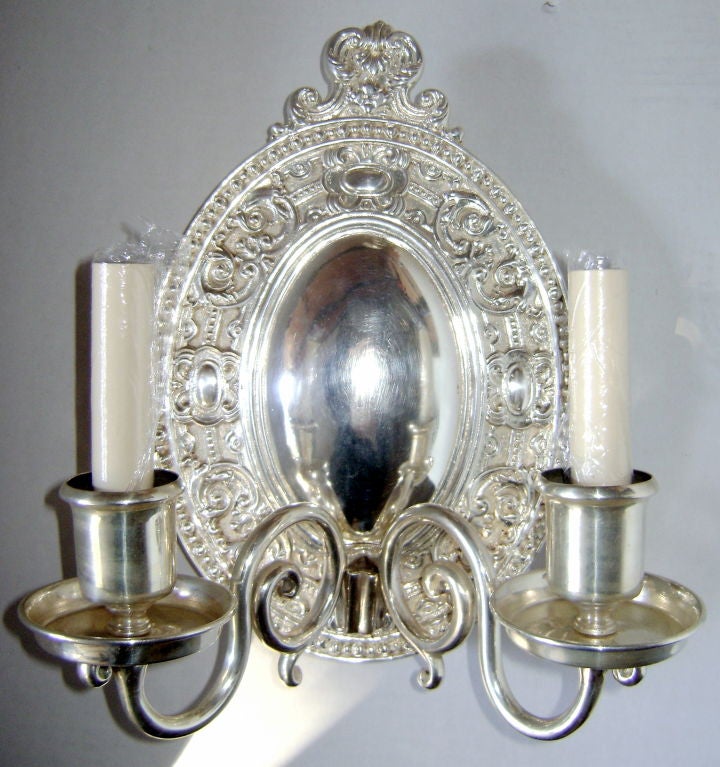 Set of American, neoclassic style, 1940s silver plated two-light sconces, scrolling motif detail on body and crown.
Measures: 12