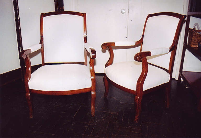 Pair of 19th century restauration walnut fauteuils, carved inscrolled padded arms, upholstered back.