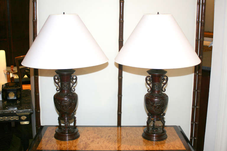 Pair of late 19th century Japanese bronze lamps, shacudo patination, raised decoration, stylized handles.