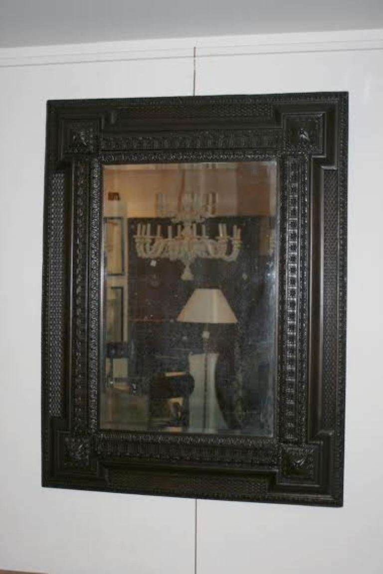 Late 19th Century ebonized walnut mirror, the plate within a carved frame of waved borders