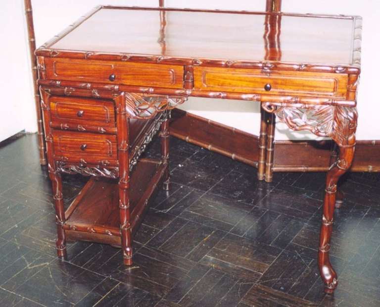 19th century Padouk-wood desk, polished top above two long drawers framed in simulated bamboo foliate brackets, the side with two small drawers and a shelf.