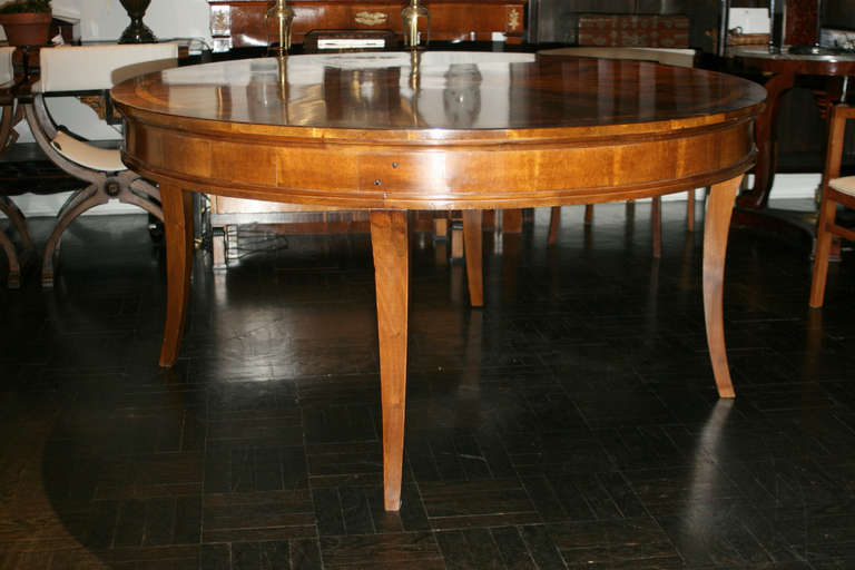 Early 20th Century center table with mixed 19th Century mahogany and walnut veneers, circular top with radiating well figured panels, outsplayed saber legs