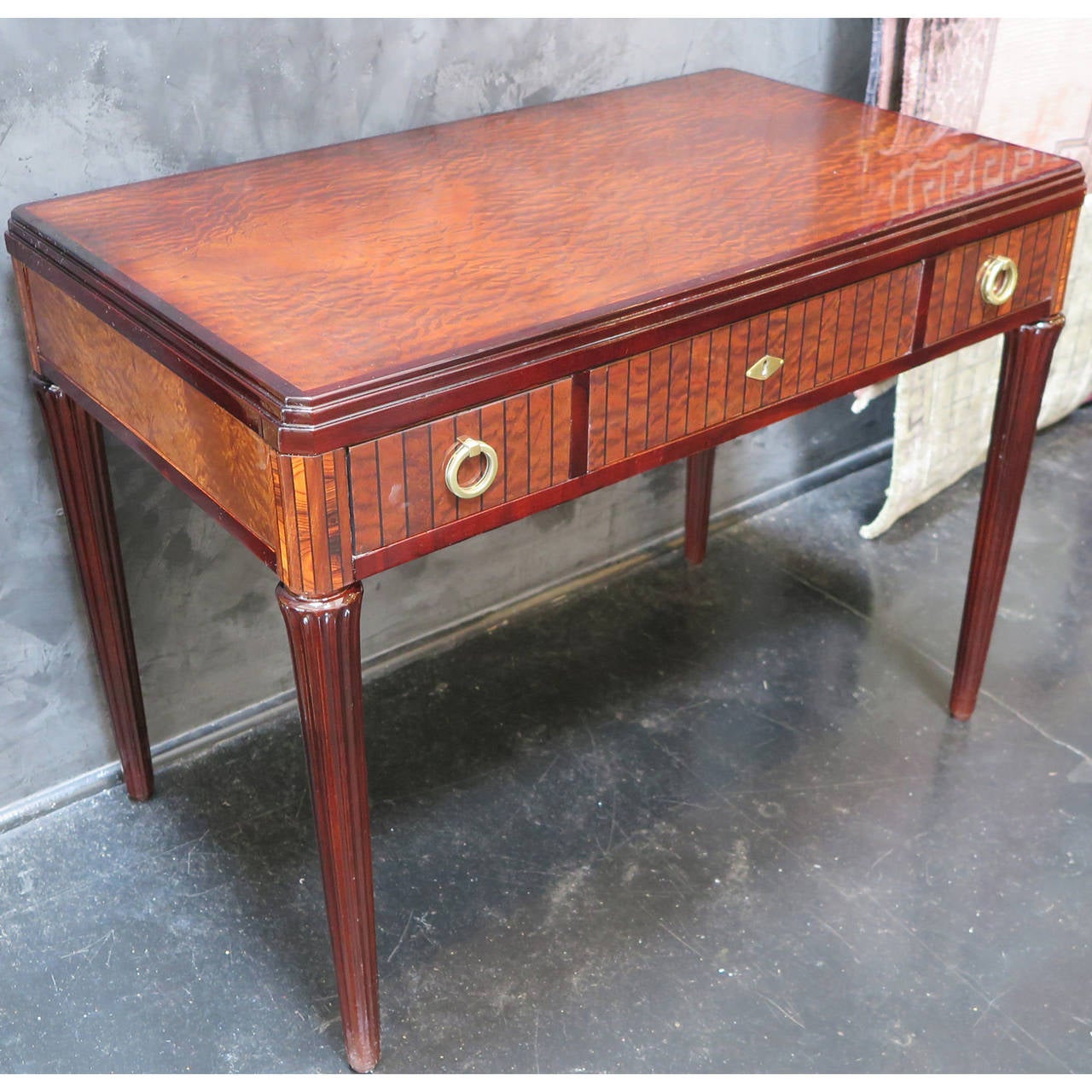 French Art Deco vanity/ desk from the 1930s. Sapele Pommele and mahogany veneer with fluted lacquer legs and marquetry detailing on edges. Original bronze hardware pulls with three pull-out drawers.