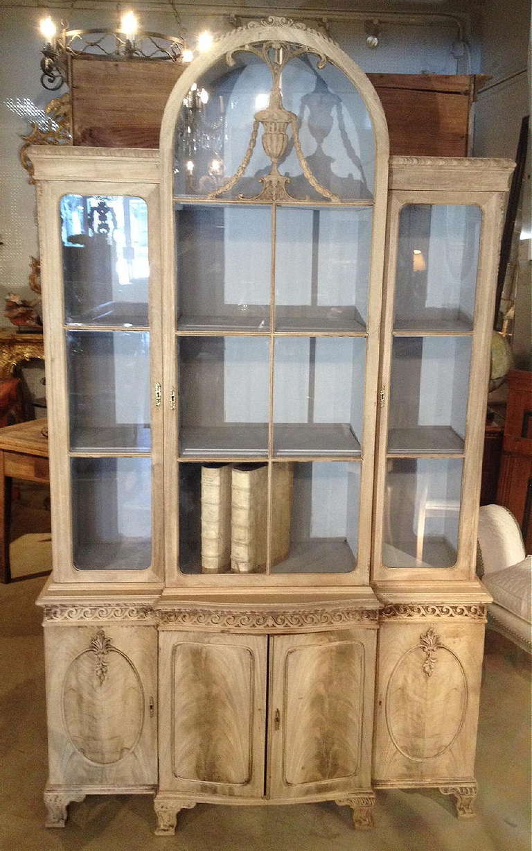 An early 20th century chippendale style breakfront or bookcase with 3 glass panel doors above 4 cabinet doors. With carved decoration and finished in a washed out mahogany.
