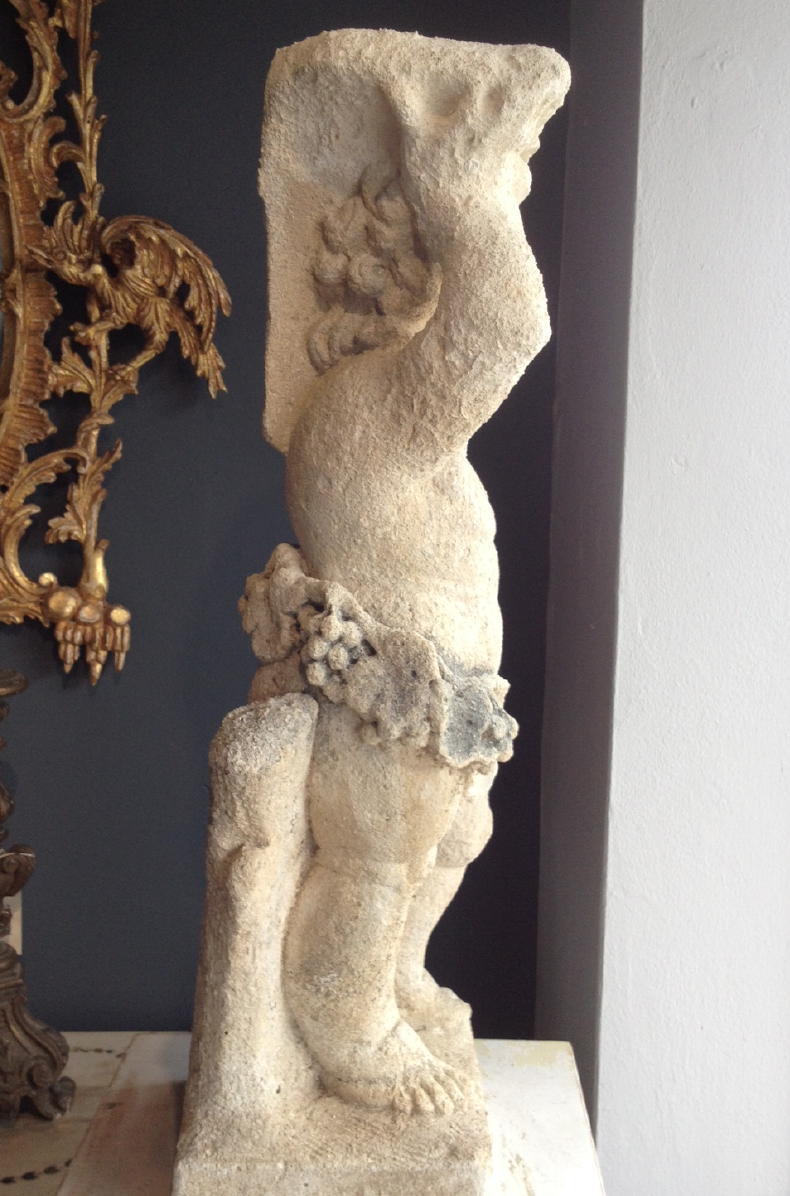 A 19th century European stone figure of a cherub. Carved standing against a tree with fruit swags around waist.