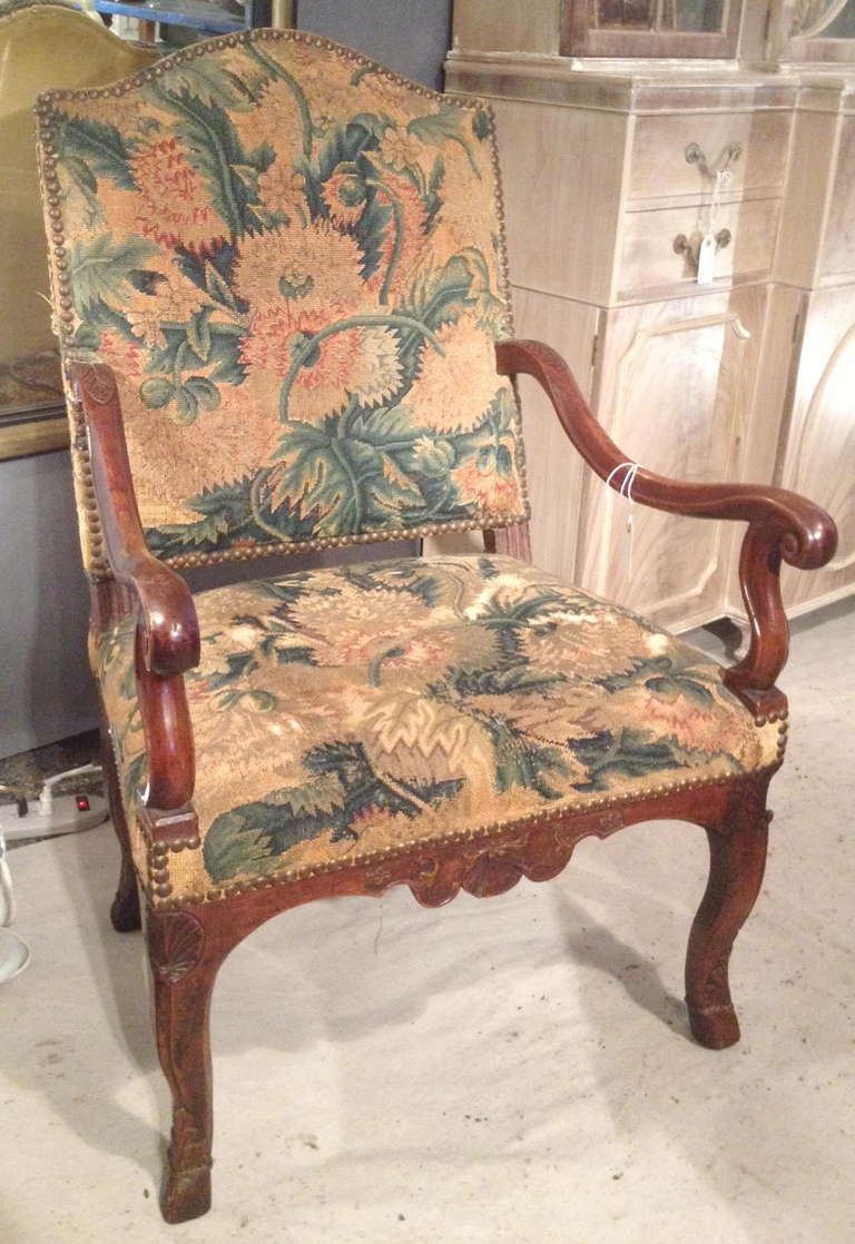 Beautiful early 18th Century French Regence armchair with tapestry upholstery, carved decoration and hoof feet.