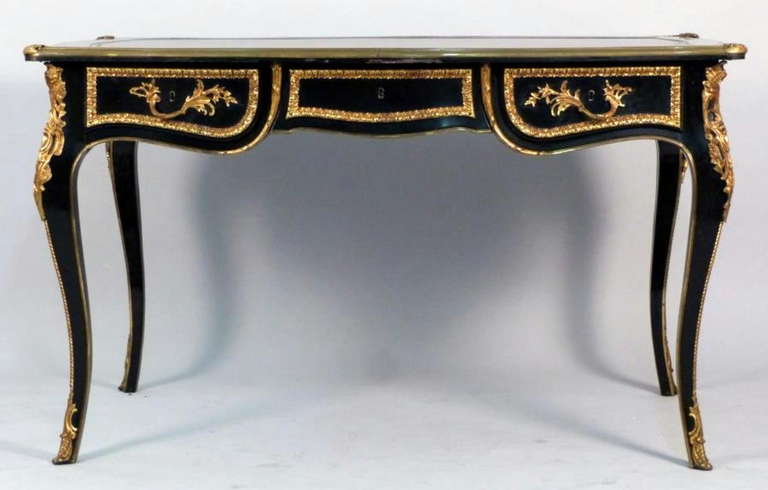 A Mid 20th Century French Louis XV Style Bronze Mounted And Ebonized Leather Top Bureau Plat With Three Drawers.