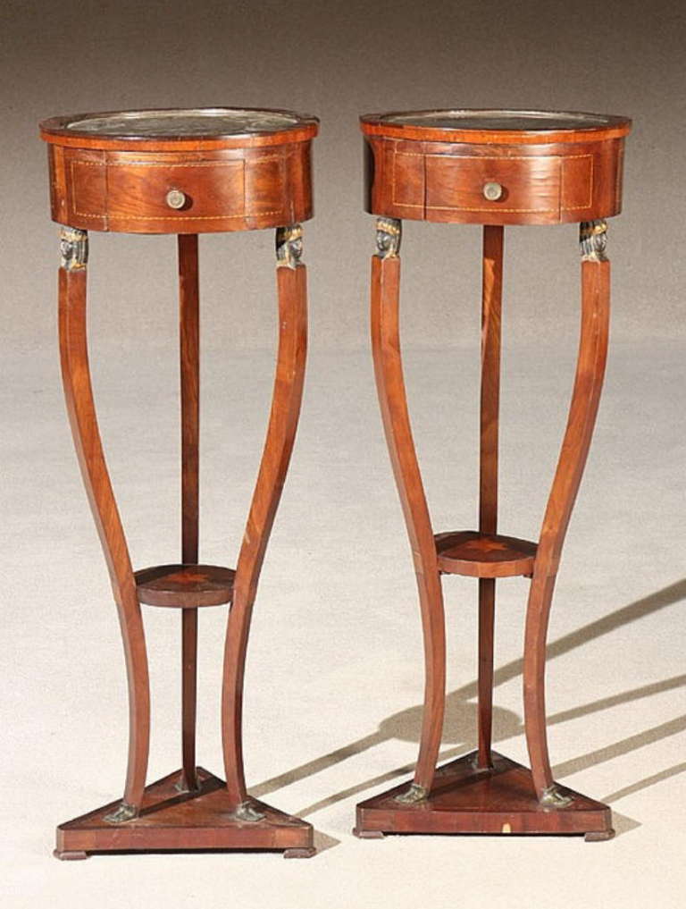 A matched pair of 19th century Italian Empire inlaid mahogany marble top stands or torchieres with carved decoration.
