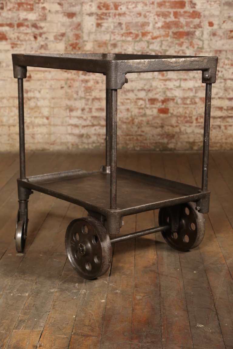 Here is a Vintage Industrial Bar Cart that takes your breath away.  The two tiers add functionality to the cast iron table.  It's original and would have been manufactures prior to World War II.  The back caster is 9