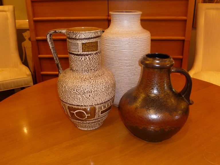 SOLD   Great grouping of three mid century German pottery pieces from three different keramik firms, each employing different techniques here.  First, the tallest is a vase from Carstens with an oatmeal textured glaze on a ribbed body.  Second is a