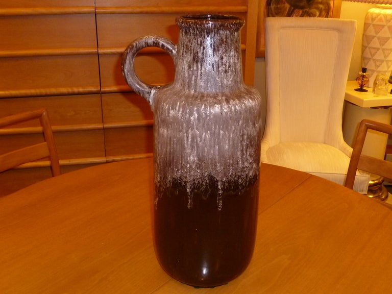 Wonderful large size, this floor vase is in the form of a krug or ewer with a nice circular handle. Great deep brown glossy glaze with an ashy appearing lava glaze drip from the top lip covering down to the mid section. A creamy frothy spume really