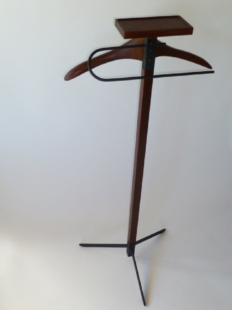 Sculptural and unique, this valet features Danish modern styling in rosewood and black patinated iron with sleek elegance. A curving iron rod for pants, sculpted hanger for shirt or jacket and top tray for accessories. Tripod iron base.

For