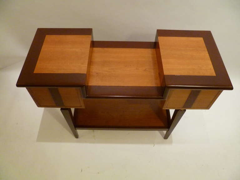 Unique architectural console table or sofa table exhibits an appealing unusual two tier top featuring bull nose molded edges in a banding style encircling warm cherry wood.  The rectangular box forms to the sides in fruitwoods with a centered