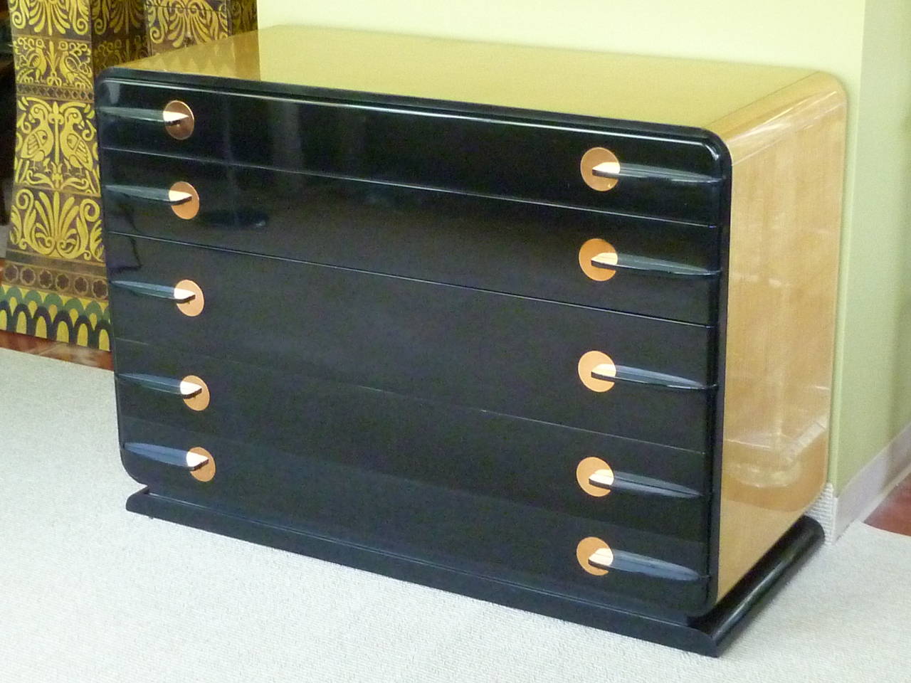 A stellar designed Art Deco streamline moderne commode with black lacquer front and lustrous harewood sides and top. In the style of Donald Deskey and Gilbert Rohde, it has subtle curves and aerodynamic lines. Featuring five drawers, the top drawer