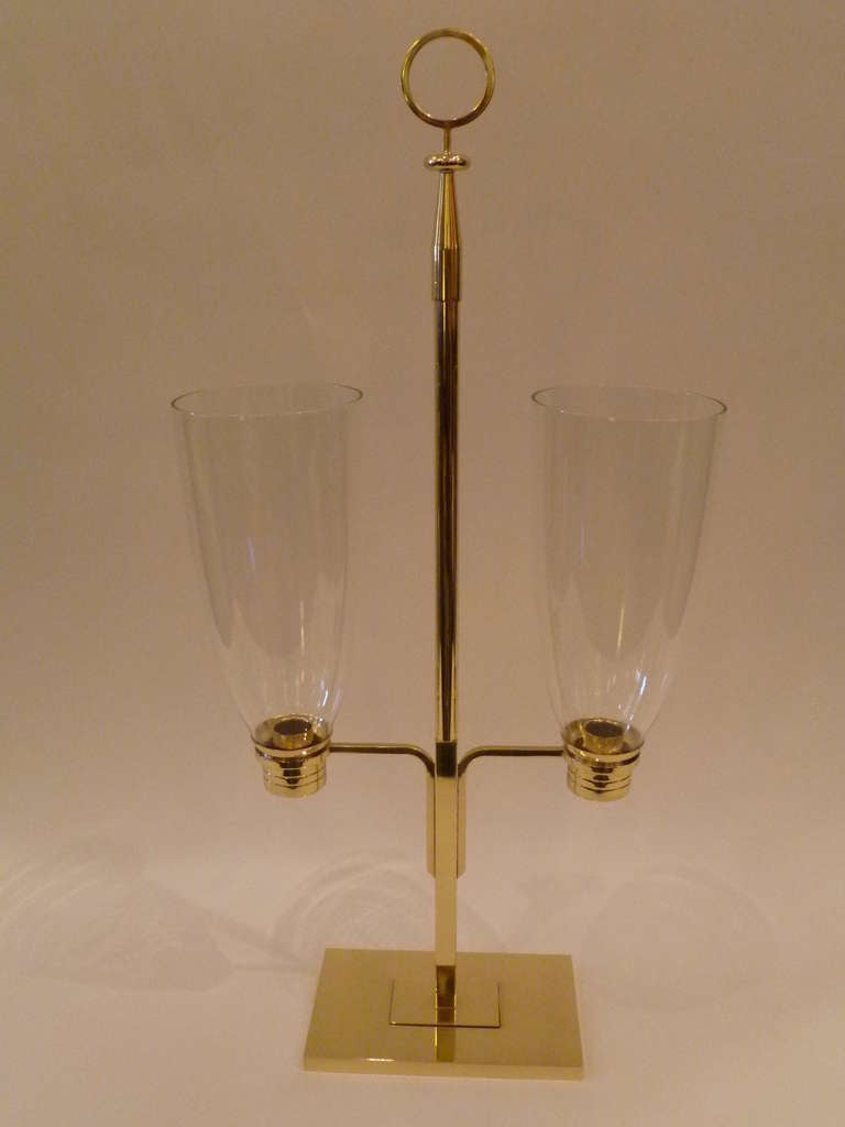 SOLD  Tommi Parzinger design for Dorlyn Silversmiths.  All original, polished brass body with plinth base, rising pole with two arms ending in cupped bobeche and fitted blown crystal hurricane globes.  The center pole continuing up to classic