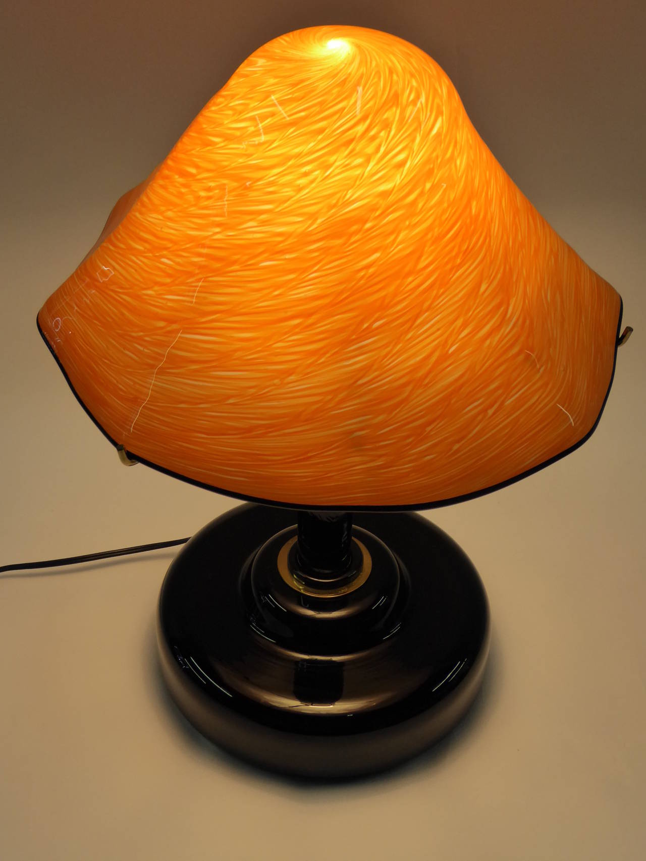 Extraordinary Fratelli Toso lamp featuring a heavy blown black glass socle base, black glass stem, brass trims and neck, with brass support arms for the orange swirl fazzoletti style blown cased glass shade. Heavy, thick and well-made. With Fratelli