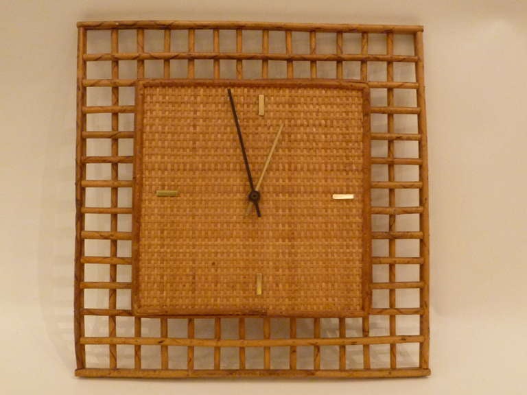 SOLD  Perfect for the beach house and from the 60s, this swell clock from Raymor has a cane back face surrounded with a framing grid of thin reed rattan.  Operating on a single 
