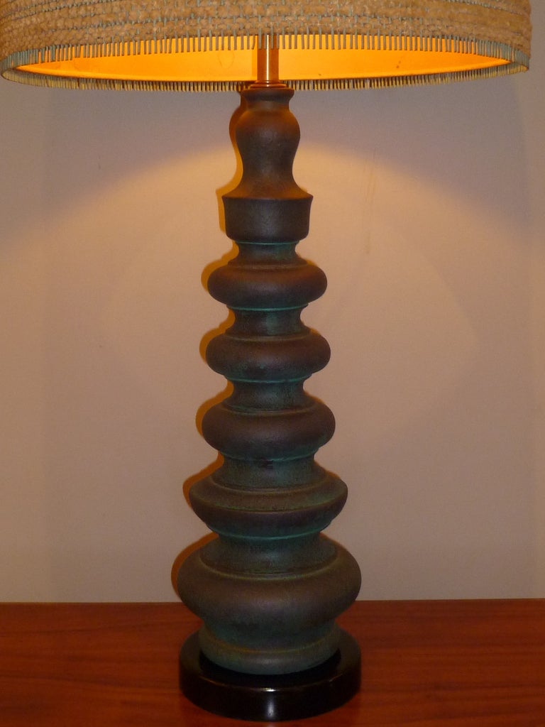 SOLD Lovely stepped Asian brass candlestick form columnar table lamp of verdigris glazed pottery on a black lacquer socle base.  Original Dorothy Liebes woven shade of turquoise dyed stick, chenille & gold metallic fiber over paper.  Shade in very