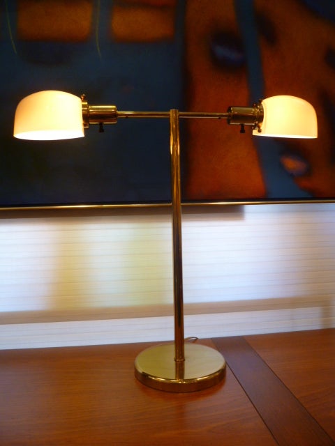 Very versatile and beautiful, this Nessen brass double light in a T form with smooth cased glass shell form globes in ivory.  Originally marketed as a library and desk lamp, it is perfect as a bedside table lamp between two beds.  In excellent