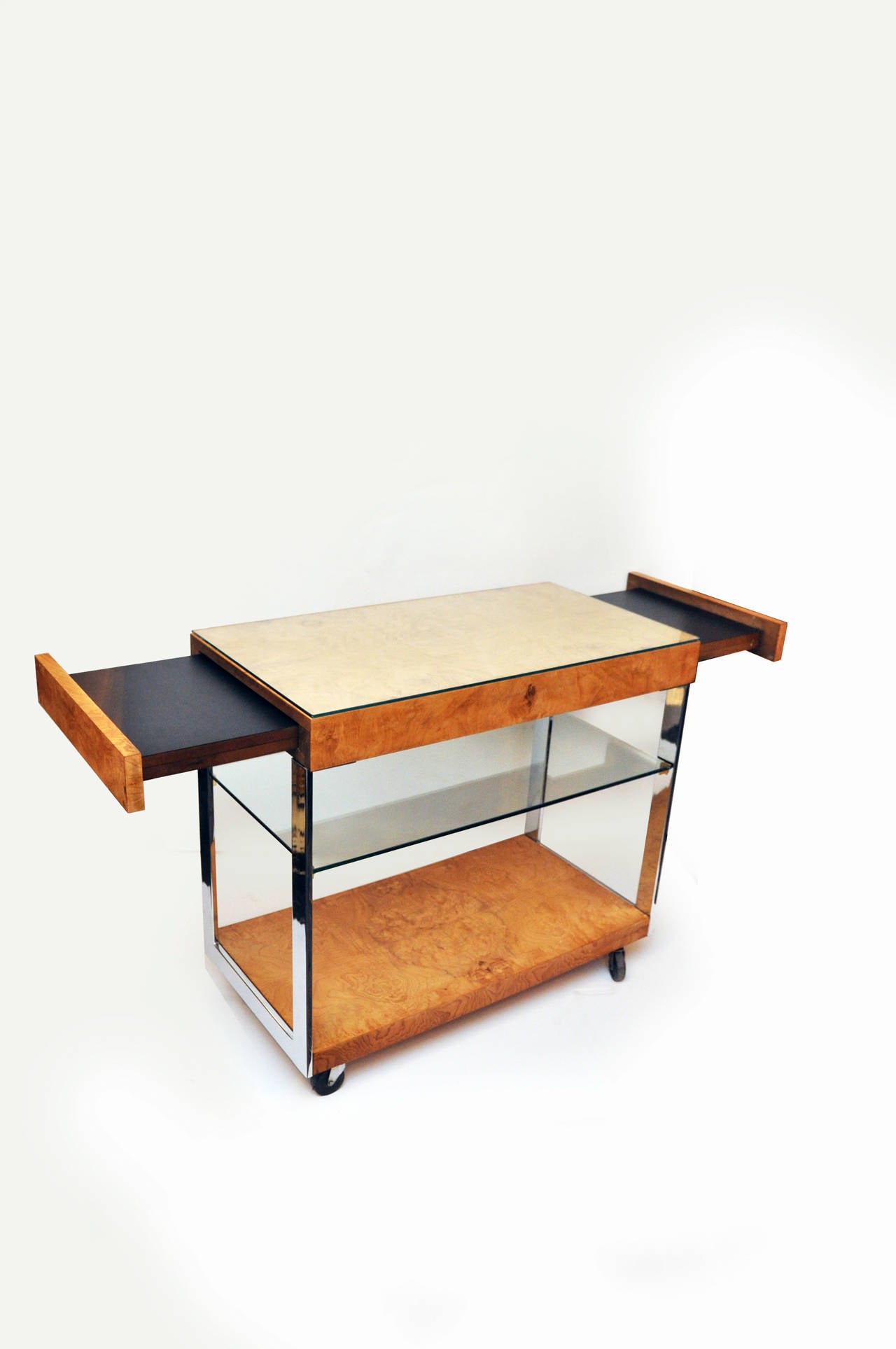 Burled wood, chrome and glass bar cart by Milo Baughman. Item features two pull-out surfaces with rolling casters, center glass shelf and glass top covering top bar surface for wood protection. When both sides are extended the cart measures 56.5