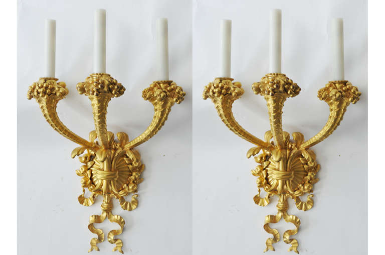 Quintessential EF Caldwell Gilded Bronze Three Light Sconces in the style of the Rocaille period. EF Caldwell was the premier designer and manufacturer of electric light fixtures and decorative metalwork in America at the turn of the 19th Century.