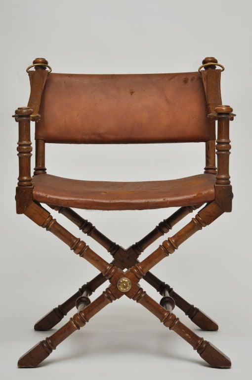 REGAL LOOKING LEATHER AND WOOD CAMPAIGN STYLE CHAIR WITH BRASS MEDALLIONS FRONT AND BACK.   DIRECTOR'S CHAIR STYLING.  DETAILS: LEATHER STRAPS WITH RING HARDWARE, OVERSIZED NAILHEAD TRIM  MADE BY DREXEL FURNITURE COMPANY IN THE 1960S.
