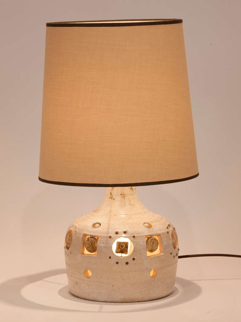 Lovely petite French ceramic table lamp by Pelletier.  Illuminated base with geometric cut out design.  Custom shade made in Paris.
