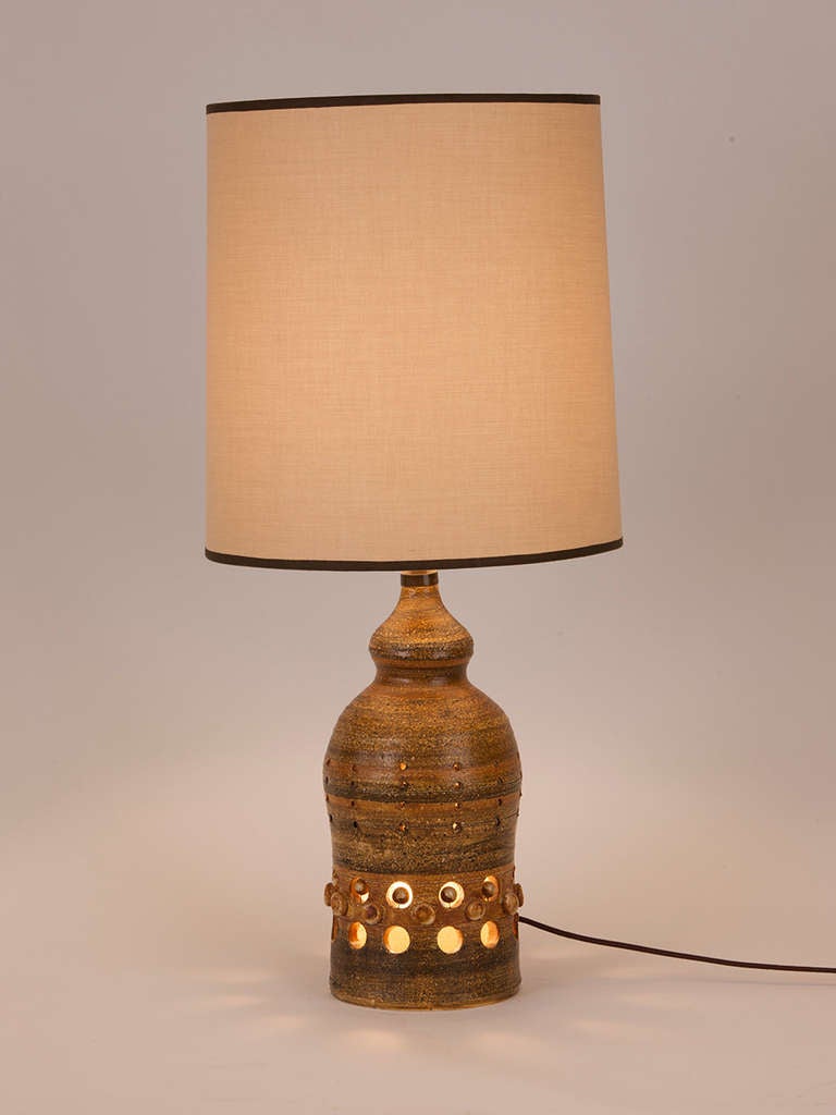 Lovely French ceramic table lamp created by Georges Pelletier.  Lamp features circular cut out motif as well as circular ceramic applique. Custom shade made in Paris.