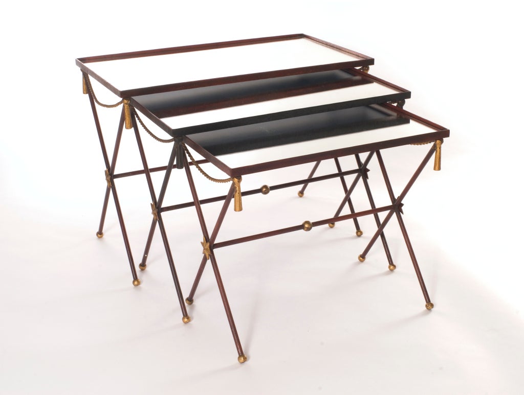 Set of three painted metal and mirror nesting table. Oxblood red is accented by gilt rope, tassel and star detail.