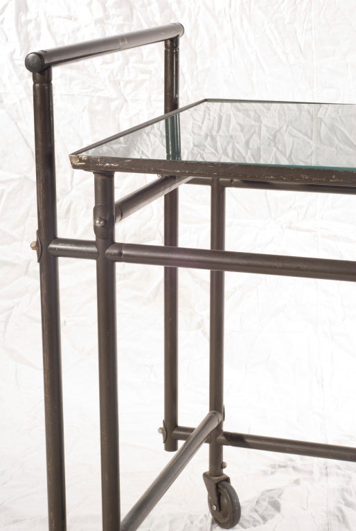 Rare industrial metal rolling cart by French designer Rene Herbst. Smoked glass tableau.
