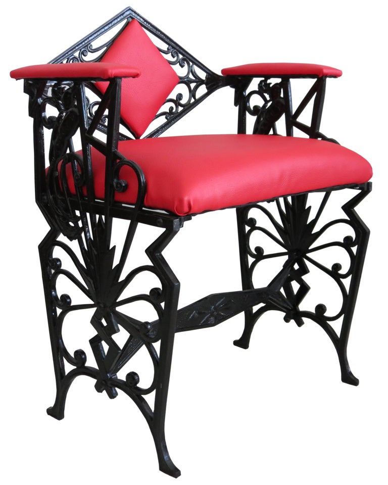 This sturdy American Art Deco cast ion bench seat is from the 1920's. the iron is finished in black which contrast with the red vinyl upholstery. On each side amongst the geometric structure is modeled a Bird of Paradise. The bench is 24