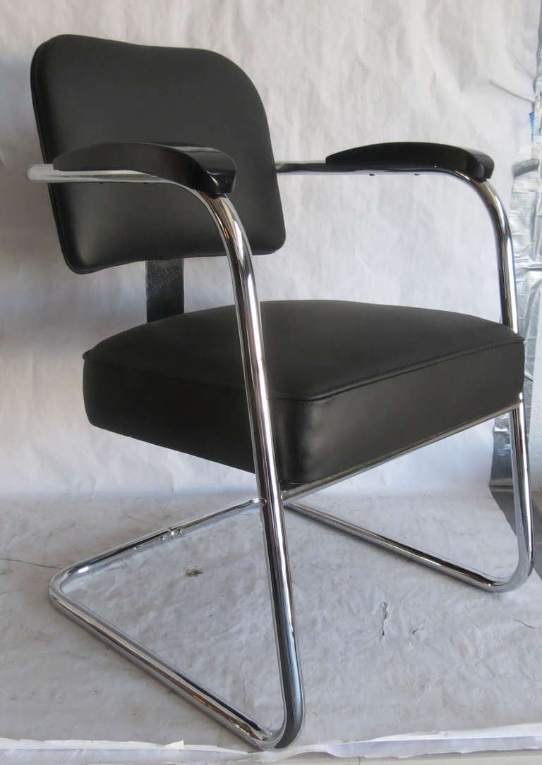 This pair of American art deco armchairs was designed by Salvatore Bevelacqua for the Mckay Company. Constructed of chromed steel tubing with a broad flat band of steel linking the seat and back, black vinyl upholstery and ebonized wood arm rests.