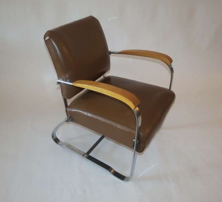 This pair of American art deco chairs was produced in the 1930s by McKaycraft Furniture for the McKay Company, Pittsburgh, PA. The chairs are machine age masculine with sturdy members of flat band steel with blond wood arms and their original light