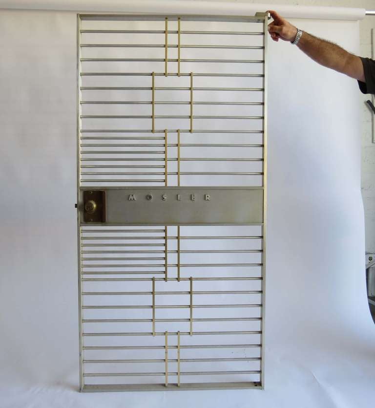This Mosler bank vault door is of polished stainless steel with brass trim. The center has in raised letters “MOSLER”/ The door would be an impressive entrance for a wine cellar or a gun cabinet. The door is 33 ½” wide and 68” high and weighs