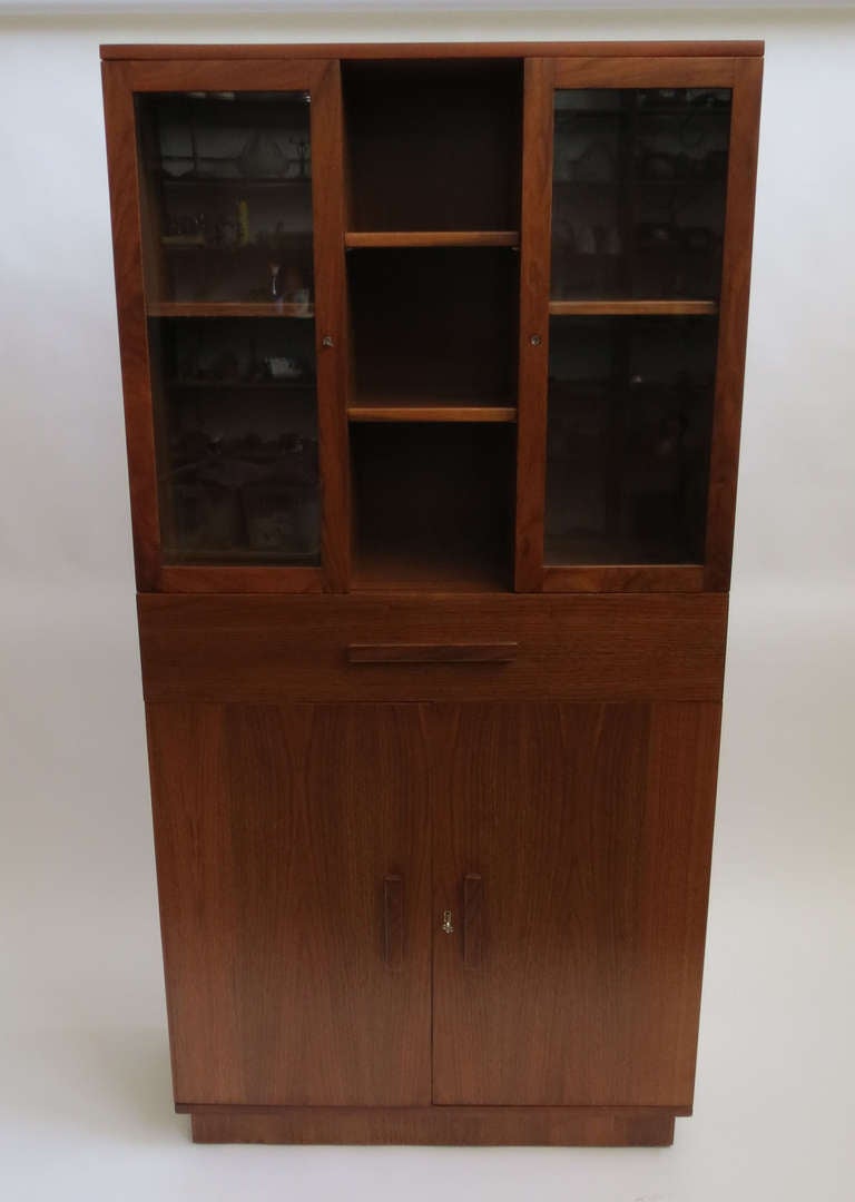 This American art deco china cabinet was manufactured and retailed by Modernage Furniture, New York ca 1933. The cabinet is of American walnut veneers with solid walnut pulls. The cabinet has an indented foot, two doors on the bottom half open to