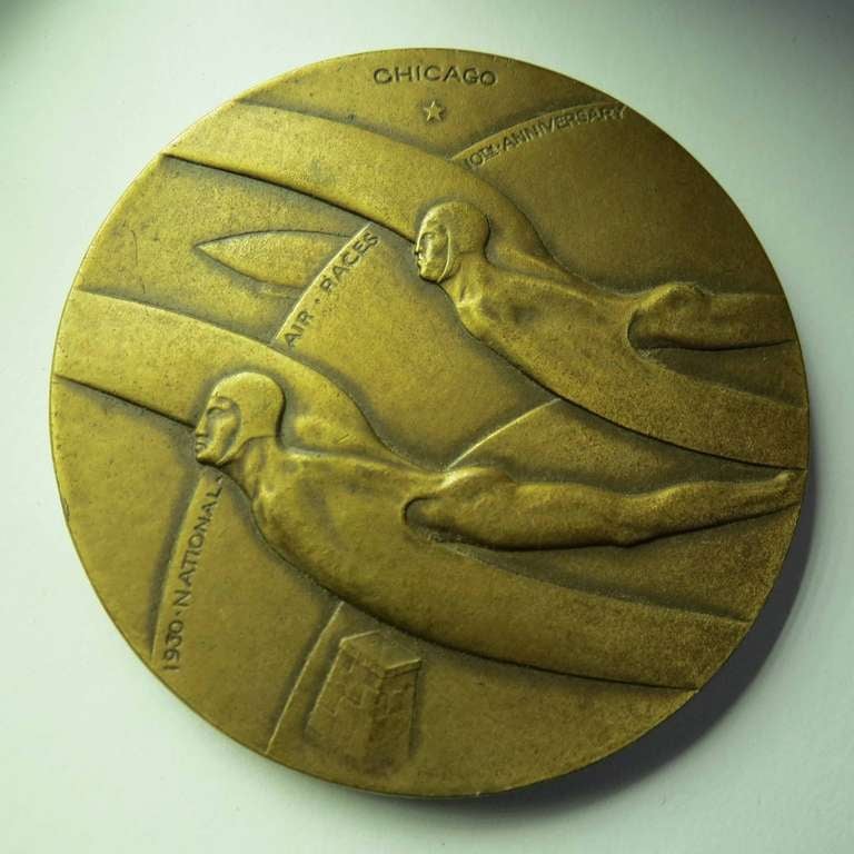 This American art deco bronze medal celebrates the 1930 national air races that took place in Chicago. It was the 10th anniversary of the races and the first year for The Thompson Trophy. The medal was sculpted by Oskar J.W. Hausen (1892-1971) who