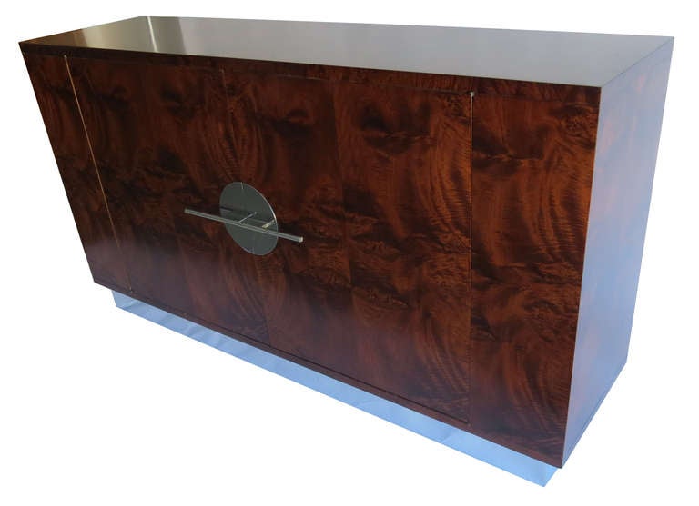 Walter Dorwin Teague (1883-1960) designed this sideboard circa 1935. It was manufactured by the Hastings Table Company of Grand Rapids, Michigan. The side board has book matched Paldao burl exterior and rests on an indented chrome steel base. The