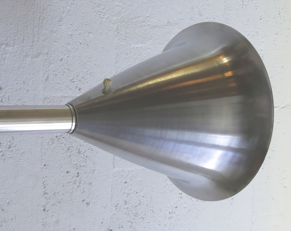 This elegant American Art Deco torchiere is from the 1930’s.  The round base sweeps up to support a thick shaft which culminates in a trumpet shade.  The lamp is constructed of polished aluminum and the base is weighted with a wood block.  The lamp