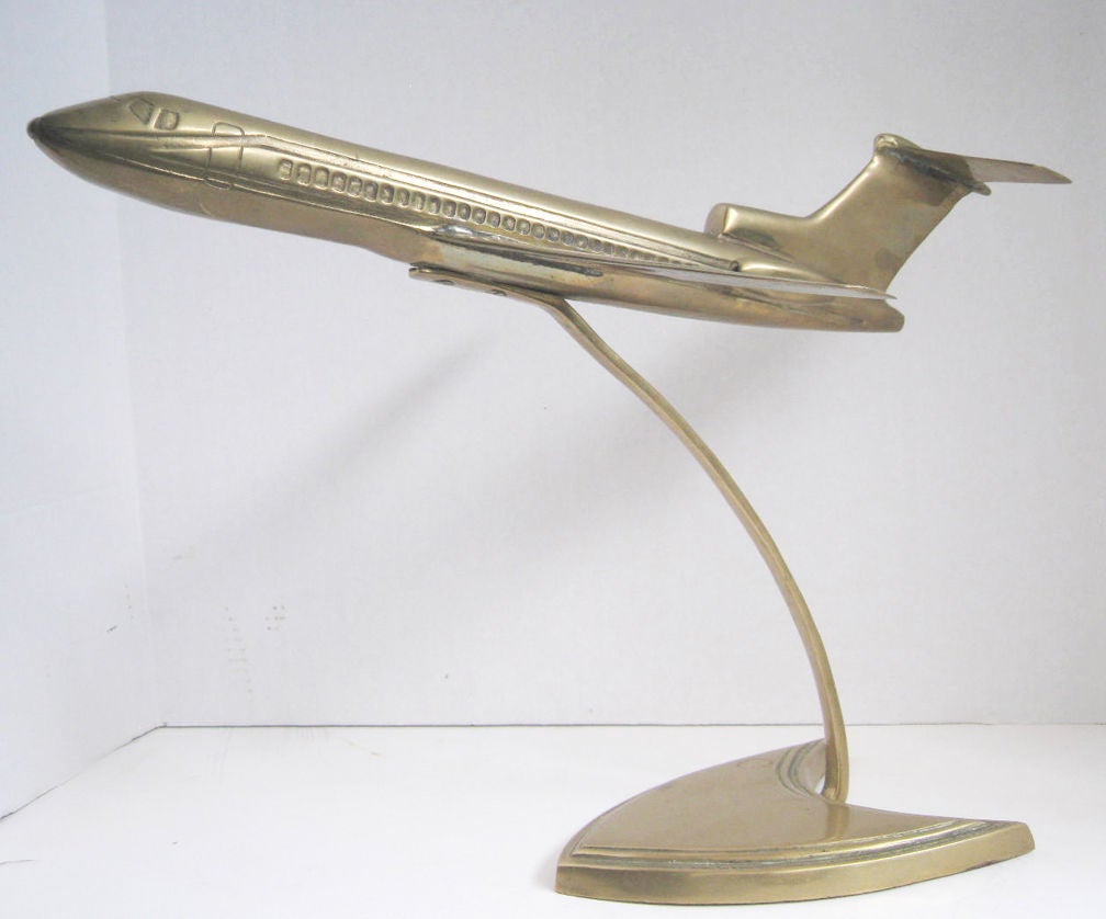 This model of a Boeing 727 jet airplane is constructed of brass. It sits 14” high on its stand. The wingspan is 13 ¼” and the plane is 18” long