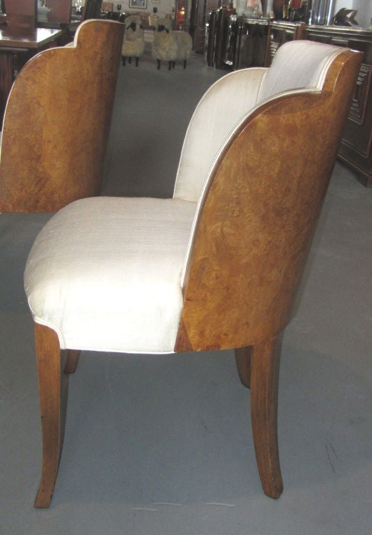 This set of four English art deco chairs was made in the 1930’s in a style made famous by Harry and Lou Epstein. The chairs are known as “cloud” style due to the scalloped and curved back. The back is burled walnut. The solid walnut legs are saber