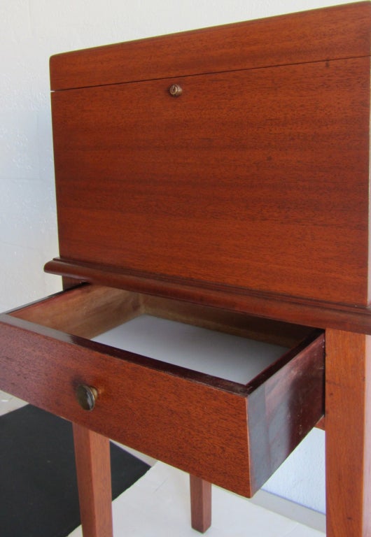 This vintage English art deco standing humidor is by Alfred Dunhill of London. The humidor is constructed of mahogany veneers and solid mahogany. The top section, which would hold several hundred cigars, is cedar lined and copper fitted with a zinc