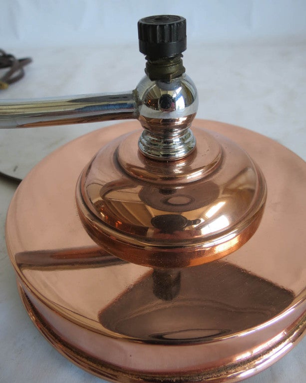This American art deco table or desk lamp is from the 1930’s. The lamp has a copper stepped base and shade and a chrome switch housing, support and finial. It has the markel blue metallic tag on the bottom and has been rewired and polished. The lamp