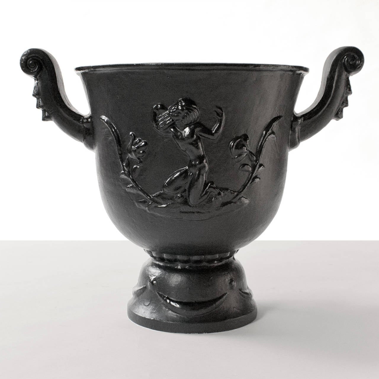 Painted cast metal Swedish art deco urn with relief of satyr playing a pan flute on one side and a woman rising from a flower on the reverse. Designed in the 1920's by Ivar Johnsson for Nafveqvarns Bruk this urn produced mid-century. Width: 17.5