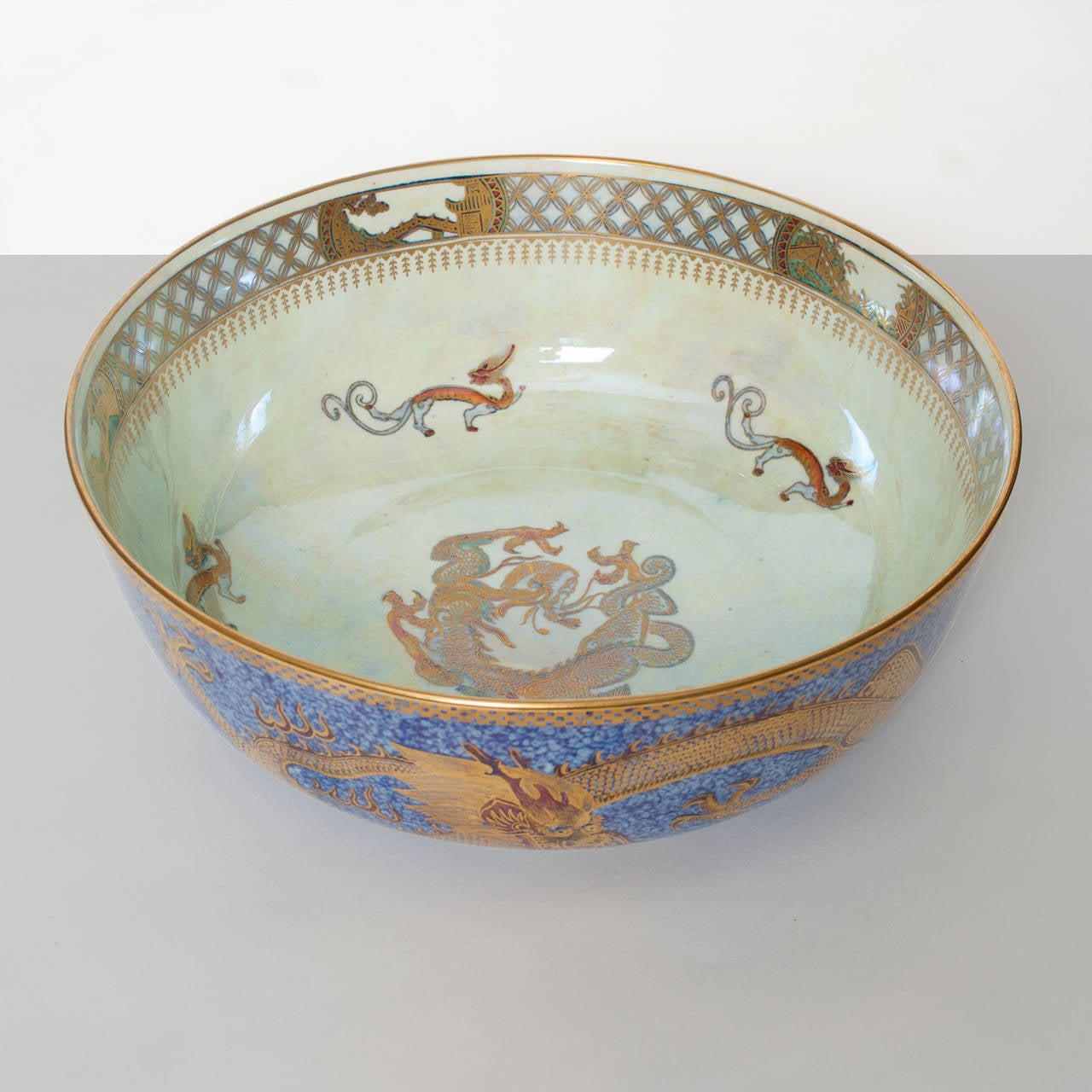 A large and very finely decorated Wedgwood Fairyland Lustre bowl designed by Daisy Makeig-Jones. The bowl's mottled blue exterior is decorated with three gilded celestial dragons and a gold dragon at the inside center along with 3 smaller dragons.