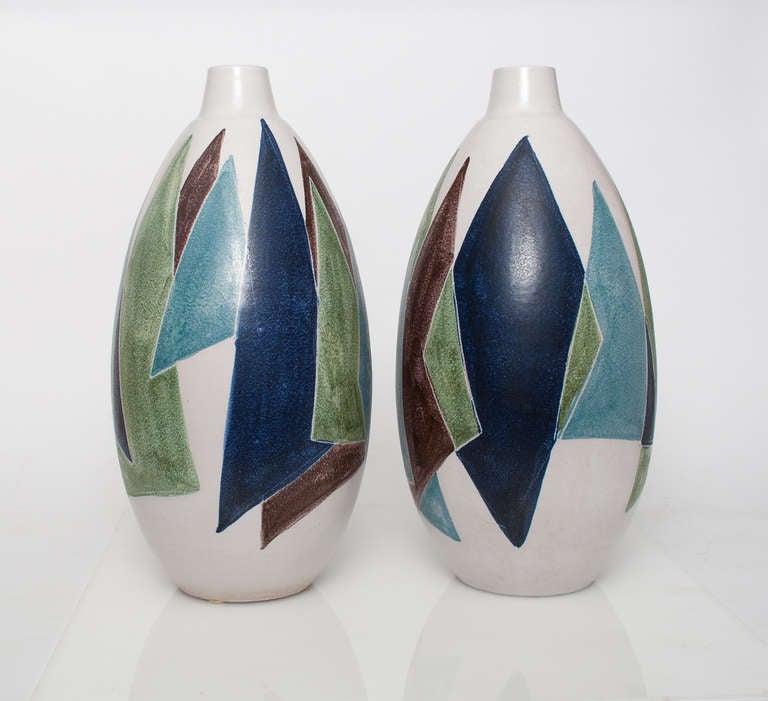 A pair of huge Swedish mid-century modern ceramic vases hand decorated by Danish artist Mette Dollar for Hoganas. Each vase has a grouping of overlapping triangular shapes in blue, green and brown on a white underglaze. Form was designed by Erik