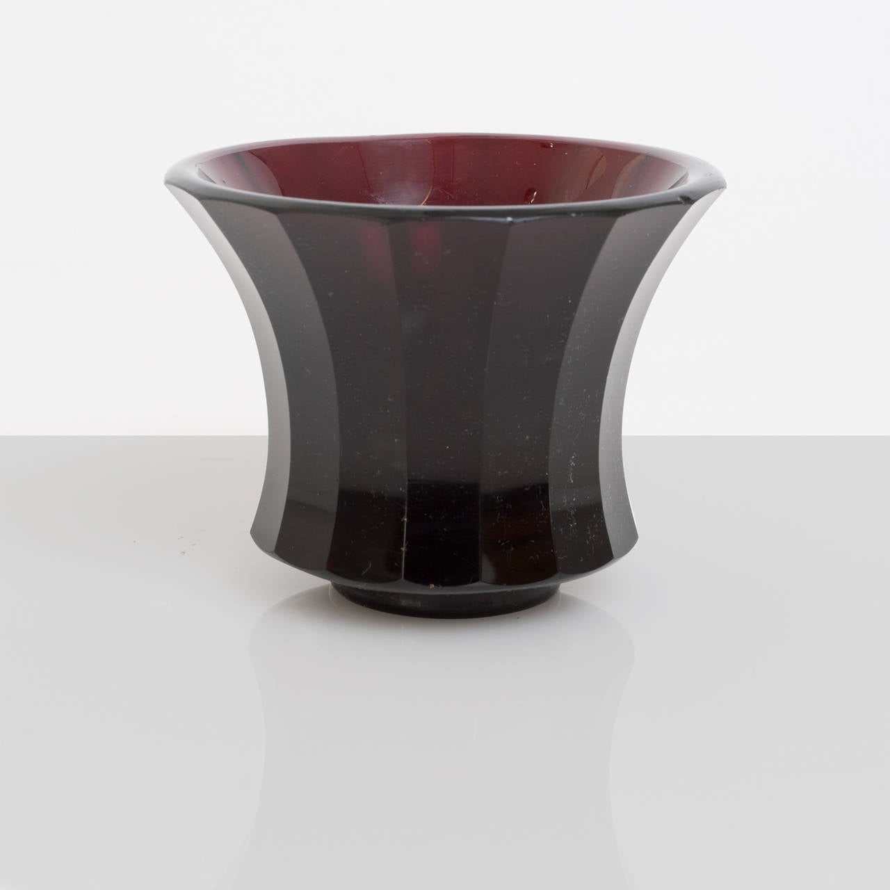 Small faceted dark red colored glass vase with highly polished surface. Attributed to Moser & Sohne, Austria. A minor chip under rim.
 
Height: 3.5", Diameter: 4.5"