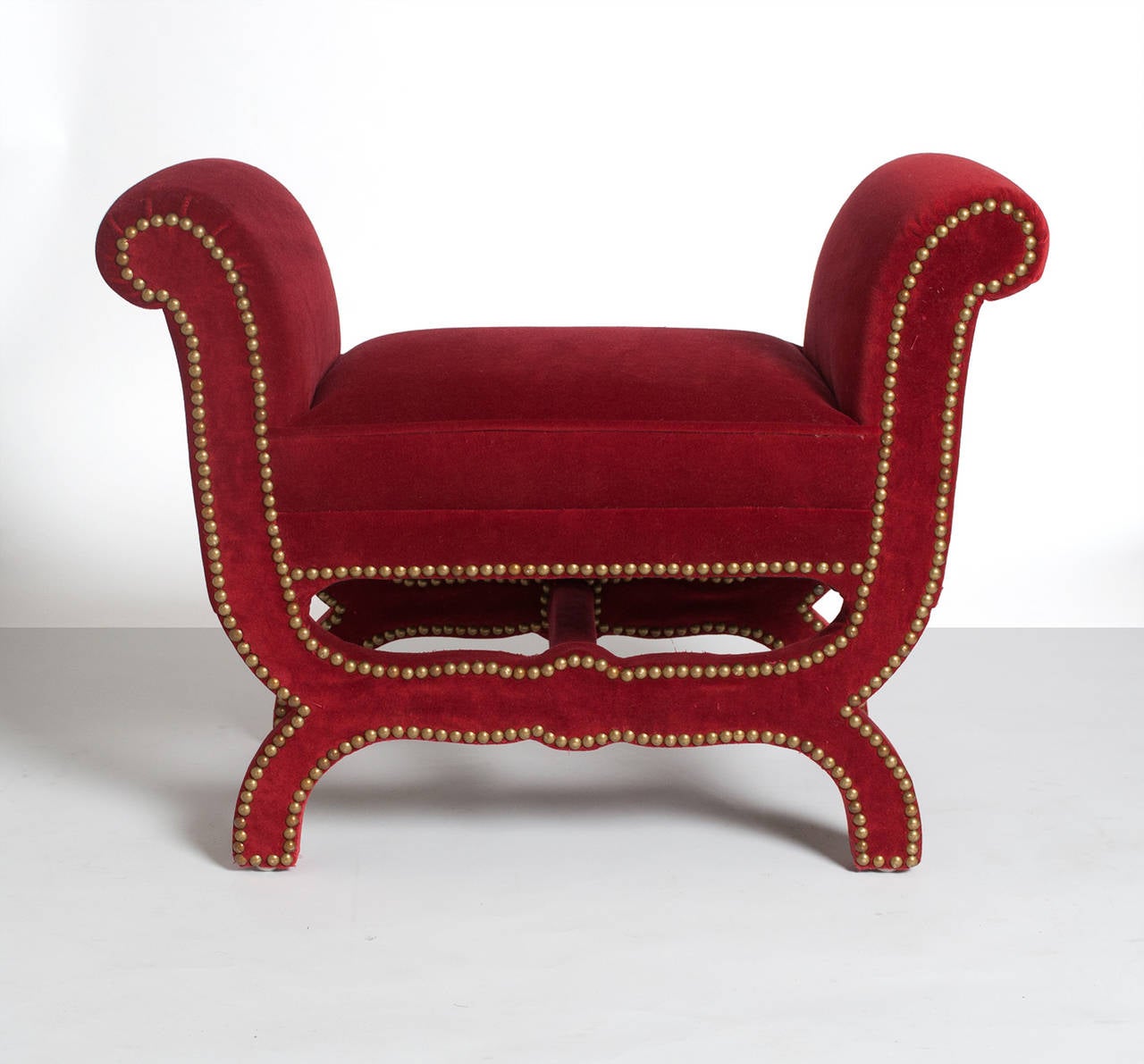 Swedish art deco footstool by Otto Schulz for Boet with scrolled design. Newly upholstered with red velvet upholstery and detailed with brass nailheads. Length: 25.5